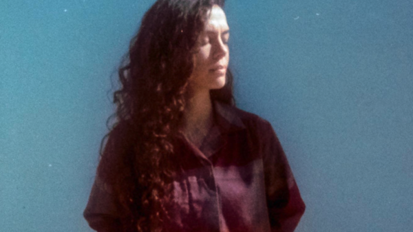 Karima stands against a blue wall